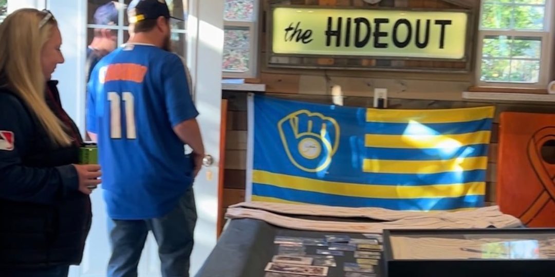 Alex Nowak and Ann Wilde in their backyard Brewers fan cave, with a Brewers flag and memorabilia on display