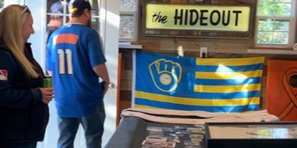 Alex Nowak and Ann Wilde in their backyard Brewers fan cave, with a Brewers flag and memorabilia on display